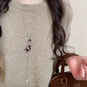 Vue détaillée du pendentif poney floqué avec perle sur une longue chaîne argentée