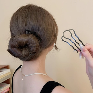 Gros plan d'une épingle à cheveux en U noir mat pour fixer un chignon élégant de femme