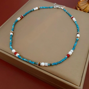 Detail of beaded necklace with blue faceted stones, white pearls, and silver clasp