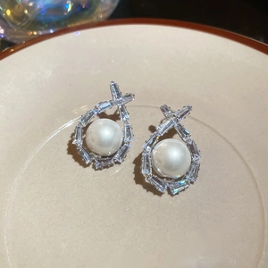 Macro shot of silver pearl earrings with baguette-cut cubic zirconia and geometric details