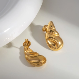 Close-up of golden conch caterpillar stud earrings with a high-polished metallic finish