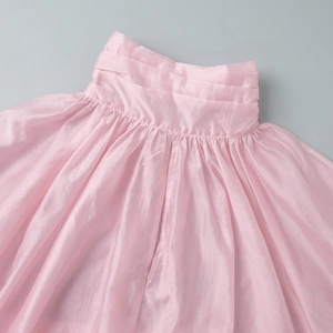 Detail of pink pearlescent organza fabric featuring layered waist pleats and ruffles