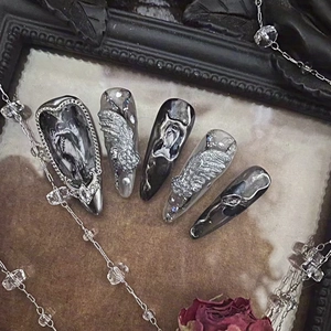 Detailed view of dark gothic press-on nails with 3D wings and heart rhinestones