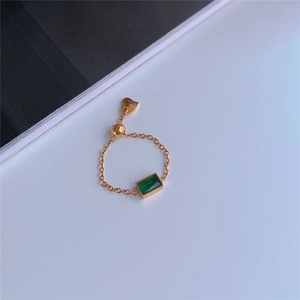 Detailed macro view of an adjustable gold chain ring featuring a green emerald zircon stone