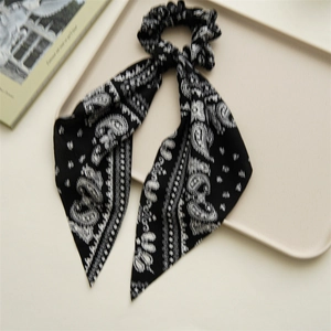 Detail of black and white paisley print scrunchie with long hanging ribbon streamers