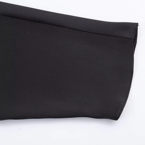 Detail of a black satin dress sleeve showing high-quality stitching and woven texture