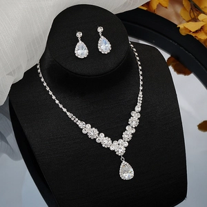 Close-up of silver V-shaped necklace and teardrop earrings with sparkling zircons on a display