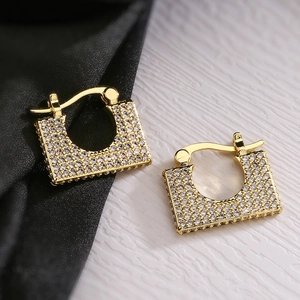 Macro shot of gold-plated U-shaped earrings with micro-pave zircons on silk background