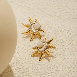 Macro detail of sun and moon stud earrings featuring gold-silver tones and opal stone