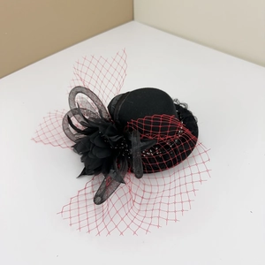 Detail of black mini fascinator hat featuring elegant red mesh veil and fabric floral accents