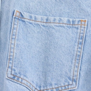 Detailed close-up of light blue denim pocket with orange double stitching craftsmanship