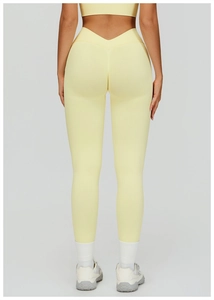 Detail view of high waisted V-shaped peach lifting seam on yellow ribbed yoga pants