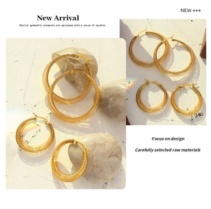 Macro shot of gold-plated spring texture hoop earrings in two sizes on stone background