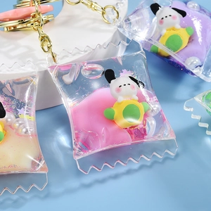 Detailed macro view of oil-filled candy bag keychain with white puppy charm and glitters
