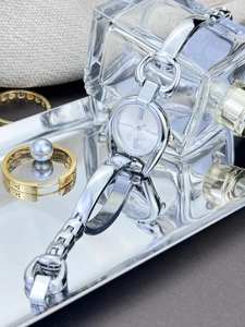 Elegant silver metal watch with roman numerals displayed alongside luxury jewelry