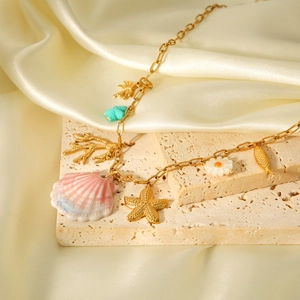 Detail of a gold ocean-themed necklace with shell and starfish charms on silk