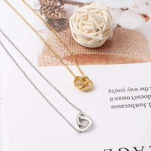Détail de pendentifs en forme de cœurs entrelacés en or et argent avec des chaînes fines