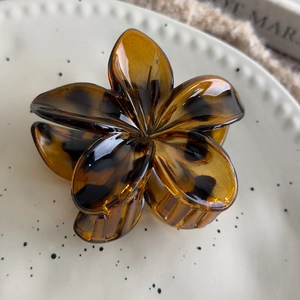 Detailed view of leopard print frangipani hair claw clip on a decorative plate