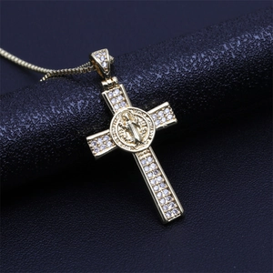 Detailed view of a gold cross pendant with Saint Benedict medal and sparkling zircons