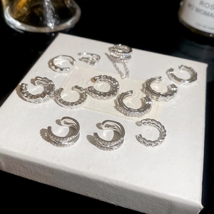 Detailed macro view of silver ear cuffs with cubic zirconia and heart designs on a white box