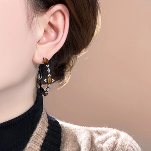 Detail of vintage C-shaped hoop earring with tiger eye stone and crystals on model