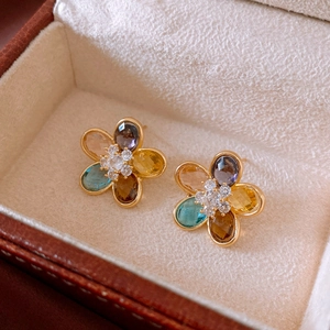 Vista macro di orecchini a fiore con gemme multicolori e zirconi in una scatola regalo