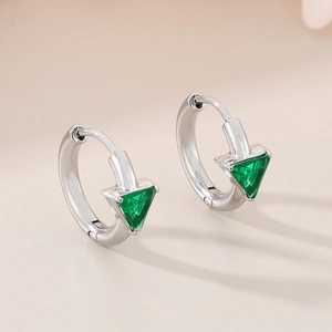 Macro view of silver hoop earrings featuring a triangular green gemstone and polished finish