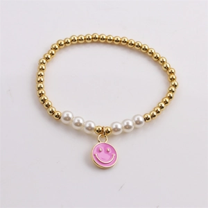 Detail of beaded bracelet with gold copper beads, white pearls and pink smiley face charm