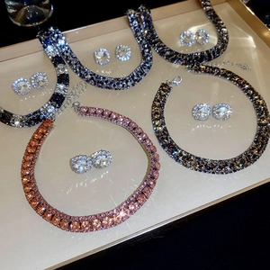 Four sets of zircon necklace and stud earrings in blue, pink, and grey on a tray