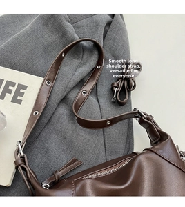 Detailed view of adjustable long strap and silver hardware on vintage brown shoulder bag