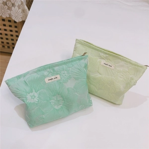Detail of mint green jacquard canvas makeup bag with 3D floral pattern and simple logo