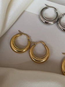 Detailed view of chunky hoop earrings in gold and silver finish on silk fabric