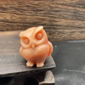 Close-up of a 3.5cm hand-carved orange owl figurine made from natural translucent stone