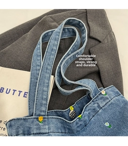 Detail der Blumenstickerei auf blauer Denim-Tasche mit Vintage-Metallknopfverschluss