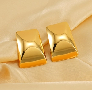 Macro shot of 18K gold plated rectangular stud earrings on luxury champagne silk fabric
