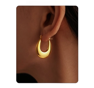 Close-up of chunky U-shaped hoop earrings with polished 18K gold finish on a model
