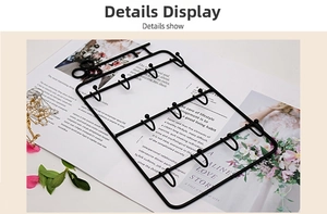 Detail view of a black metal wall-mounted jewelry organizer with ten storage hooks