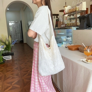 Détail du sac cabas en dentelle blanche montrant la texture fleurie et la grande taille