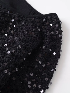 Dettaglio della giacca nera con paillettes che mostra la trama e i riflessi lucidi
