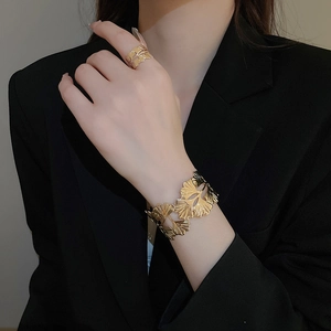 Detailed view of gold leaf pattern cuff bracelet and matching ring on model wrist