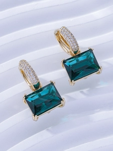 Detail of emerald green rectangular zircon earrings with micro-paved gold finish settings