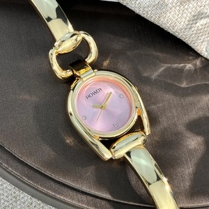 Detail of golden horseshoe case watch with pink dial and diamond markers on silk