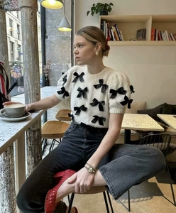 Detailansicht weißer Strickpullover mit schwarzen Schleifen und Puffärmeln
