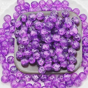 Macro shot of 10mm purple cracked glass beads with gold wire detail on a wooden tray