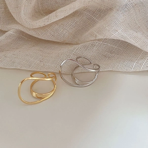 Detailed close-up of double-layered irregular gold and silver open rings on linen