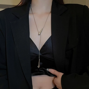 Close-up of minimalist silver water drop pendant necklace worn with a black blazer