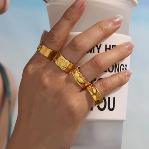 Set of four gold stainless steel rings with smiley and hammered texture on hand