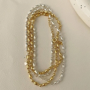 Minimalist 925 sterling silver bead necklaces in gold and silver finish stacked on a surface