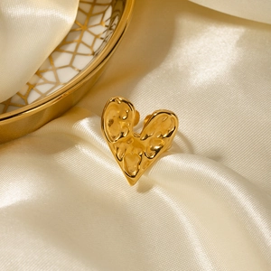 Detail of 18K gold stainless steel heart ring with hammered texture on silk fabric