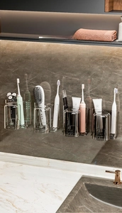 Detail of wall-mounted toothbrush holder with four grey drainage cups and sleek organizer